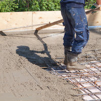 Laborer pouring concrete over rebar
